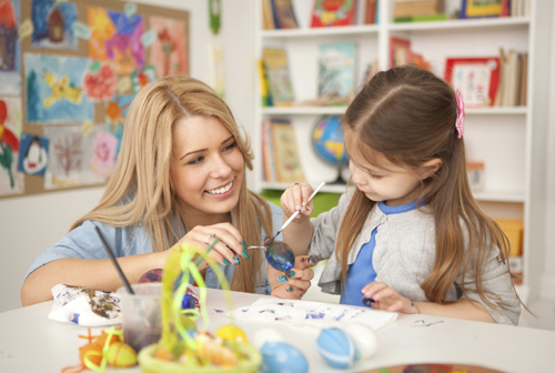 teacher painting egg with girl