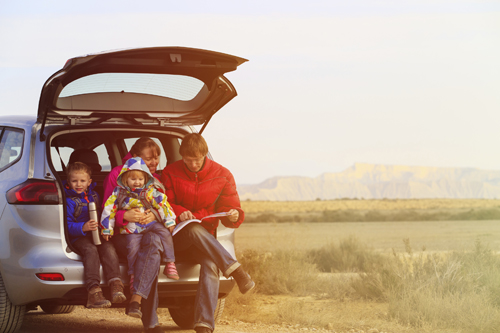 young family sitting in car on side of the road