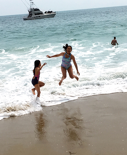 two girls jumping in the ocean