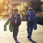 two young boys walking home from school with backpacks on Thumbnail
