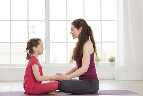 young girl meditating with woman