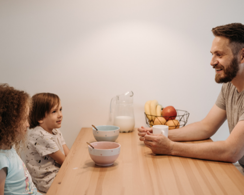 dad talking to his children at breakfast table