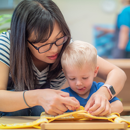 LePort - teacher helping a toddler with arts and crafts