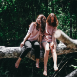 two girls sitting on a tree branch