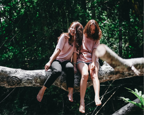 two girls sitting on a tree branch