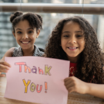 Two girls holding thank you sign