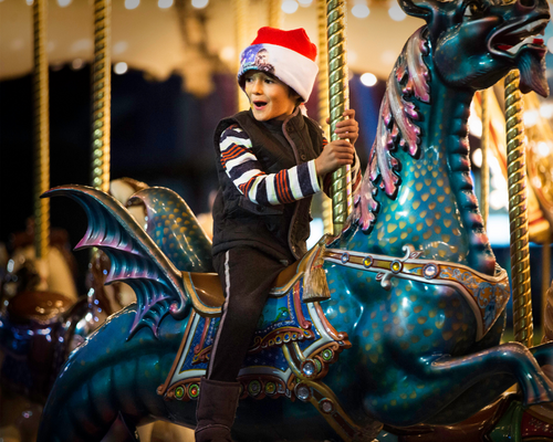Boy in Santa hat riding Mary-Go-Round horse