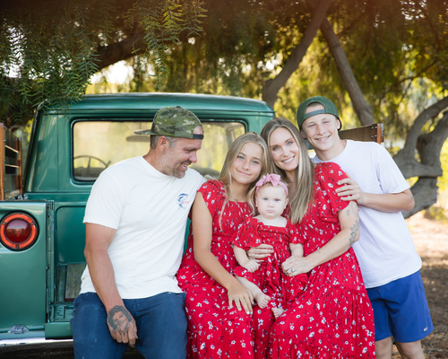 Brittany Eastwood with her family by a green truck and red dresses 