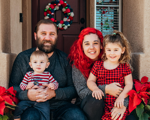 Katie Hart with her family on front porch with red and green Christmas decorations 