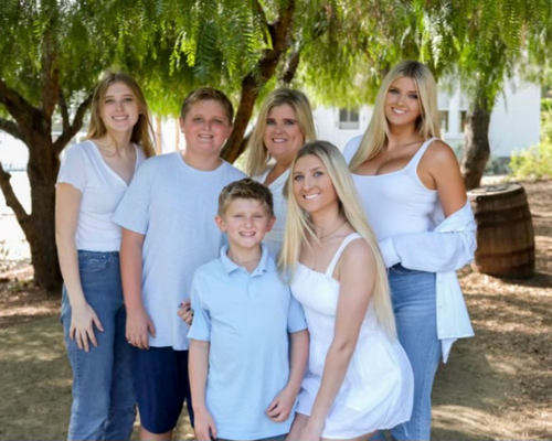 Marisa Draper with her family in front of green tree background