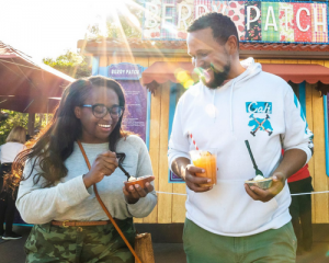 a smiling man and a smiling woman eating desserts at Disney California Adventure Food & Wine Festival