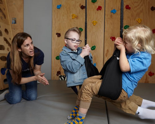 Avital Shuster, pediatric occupational therapist and the clinical director of Tumble 'N Dots guides Connor and Eli on the helicopter swing
