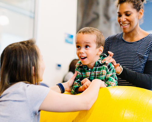 Two smiling women rehabilitating a smiling kid