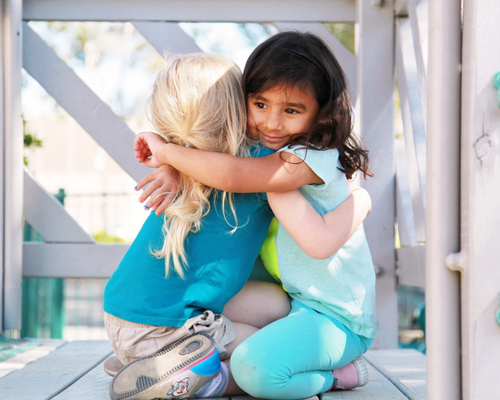 Two-students-embrace-on-the-playground-at-LMA-RSM