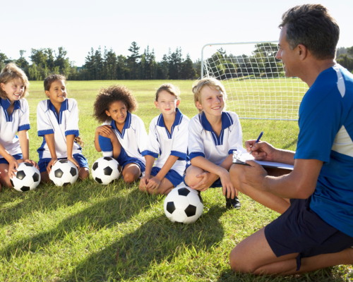 Kid soccer team on soccer field listening to coach's instructions