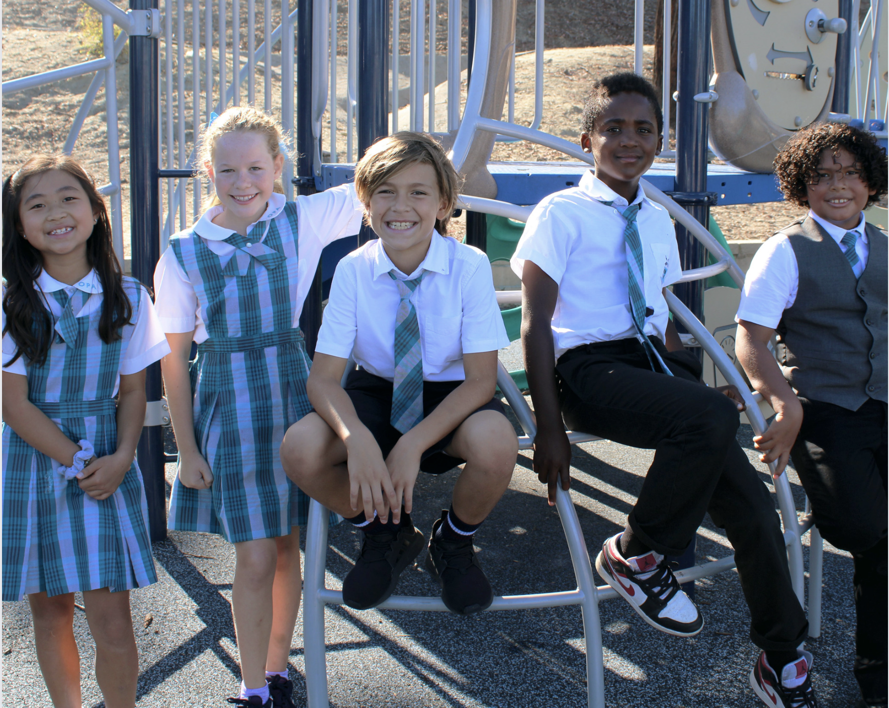 Students in uniform smiling on a playground at Oxford Preparatory Academy Best Charter School