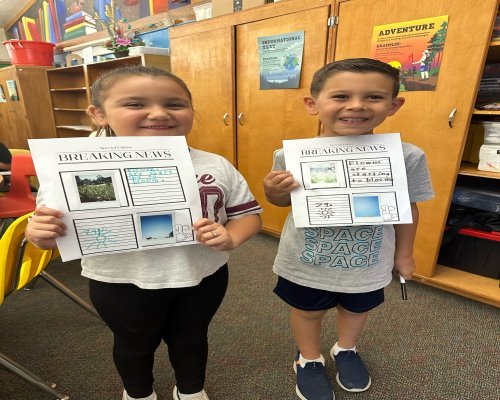 Two kids holding up their projects