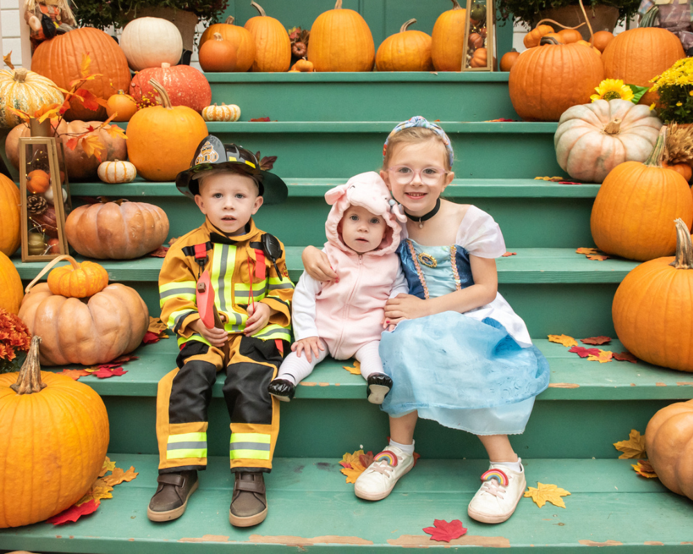 Three little kids in Halloween costumes are taking photos at the photo shoot opportunity at the Heritage Hill Fall-O-Ween event. 