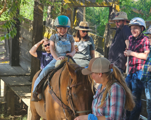 A young rider is ready, as her brother cheers her on.