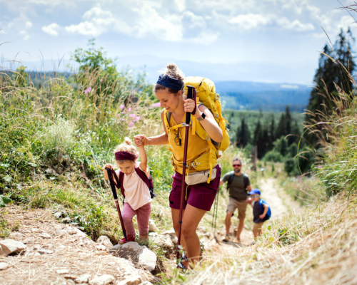 Mom helping daughter hike over small rocks on a trail