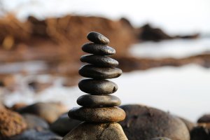 Rocks balanced on top of each other with a lakeside backdrop.