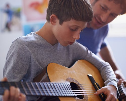 kid being taught guitar